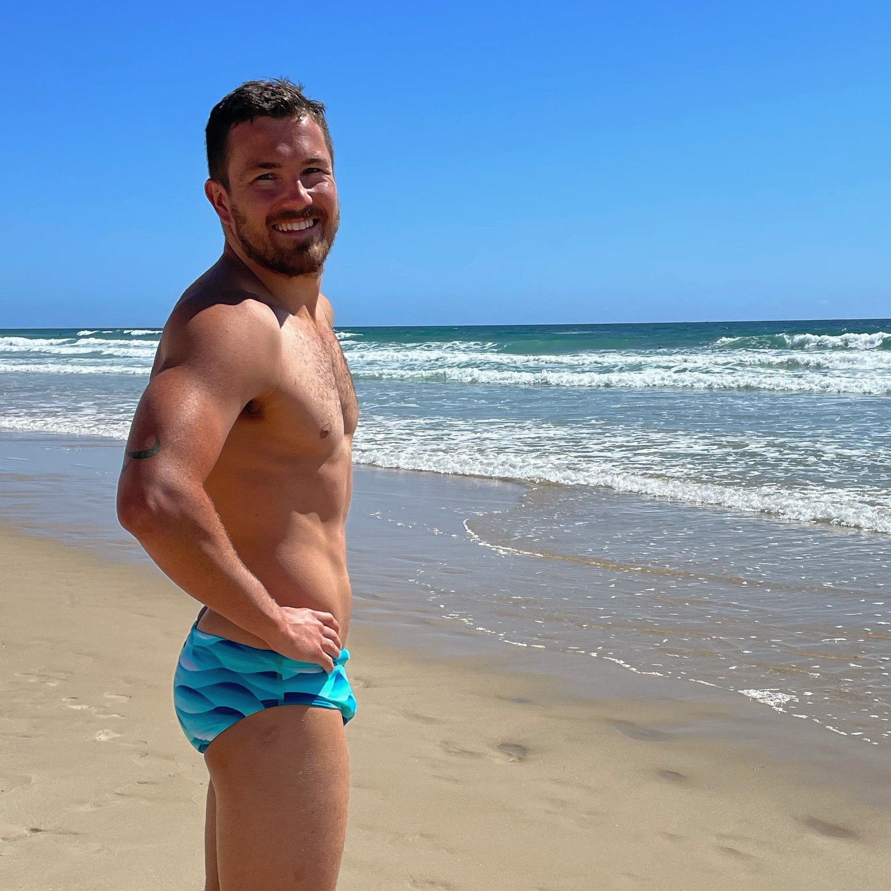 Swimmer at the beach with hands on hips smiling