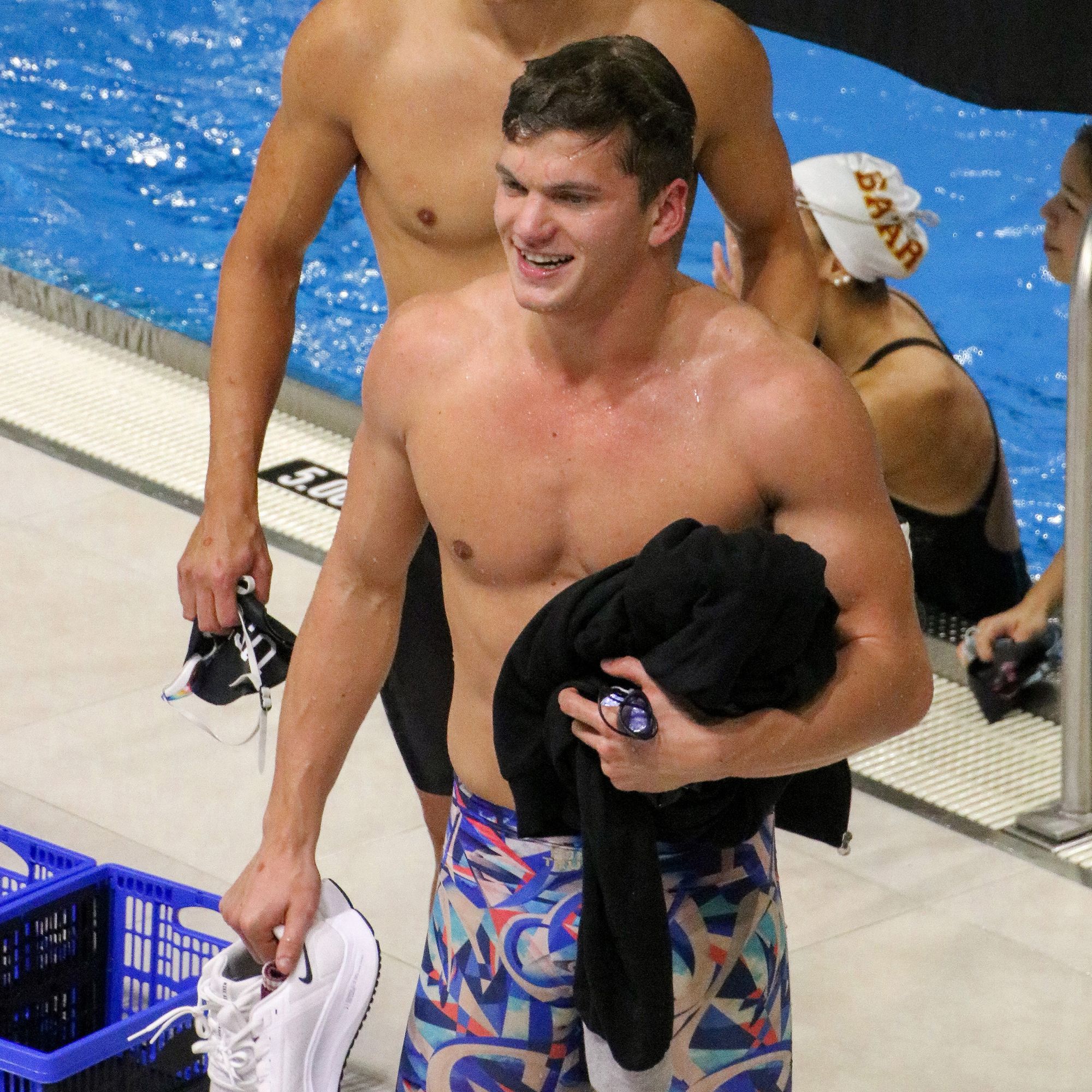 swimmer walking on pool deck in a race suit