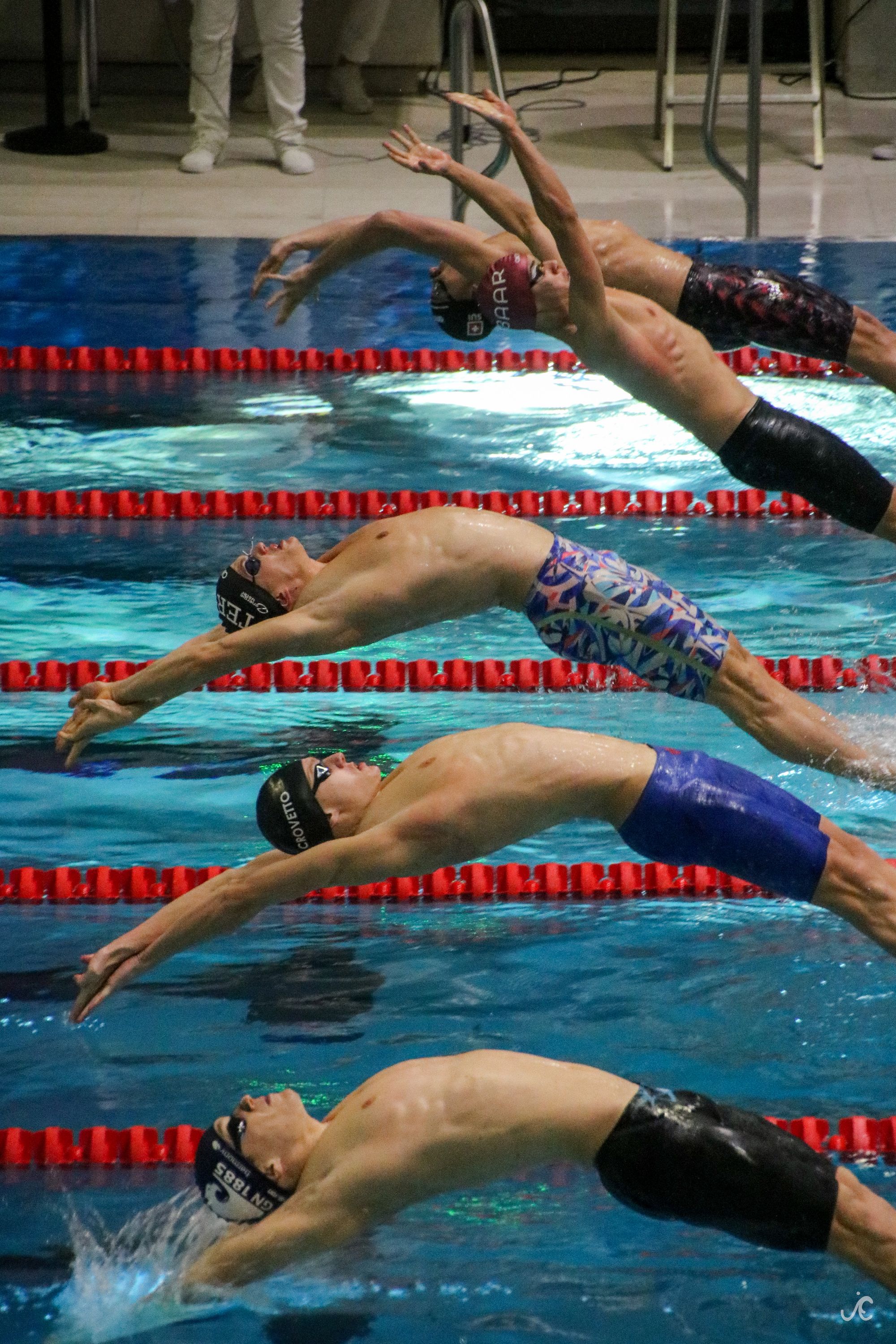 Swimmers doing a backstroke start at a swim meet.
