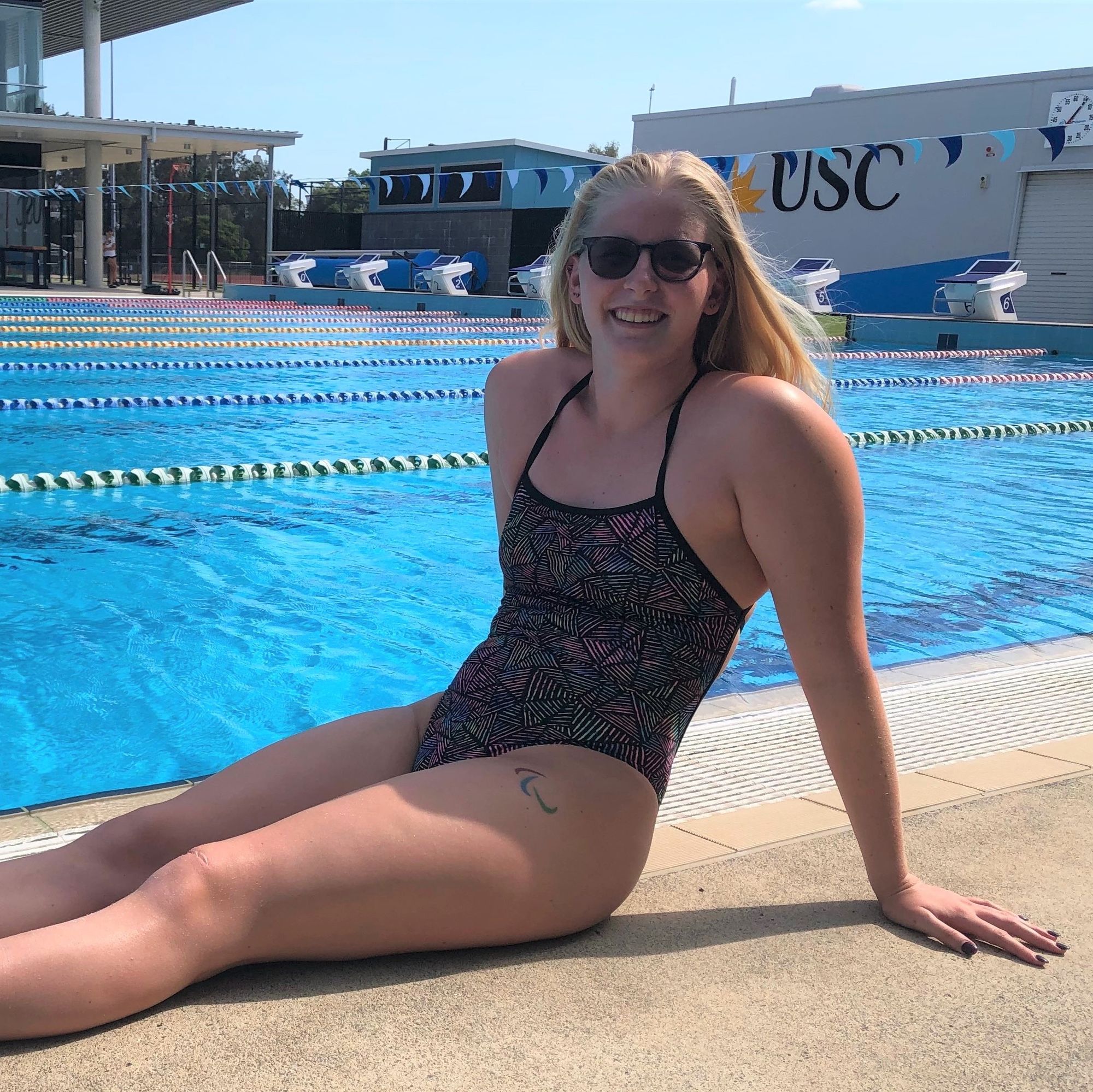 swimmer sitting on pool deck with glasses on